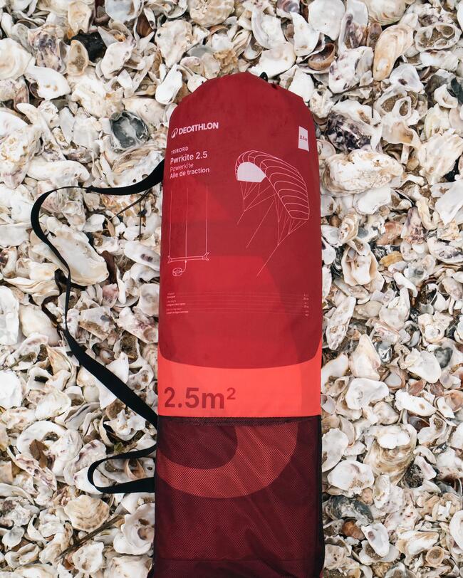 aile de traction rouge dans son sac, posée sur des coquillages
