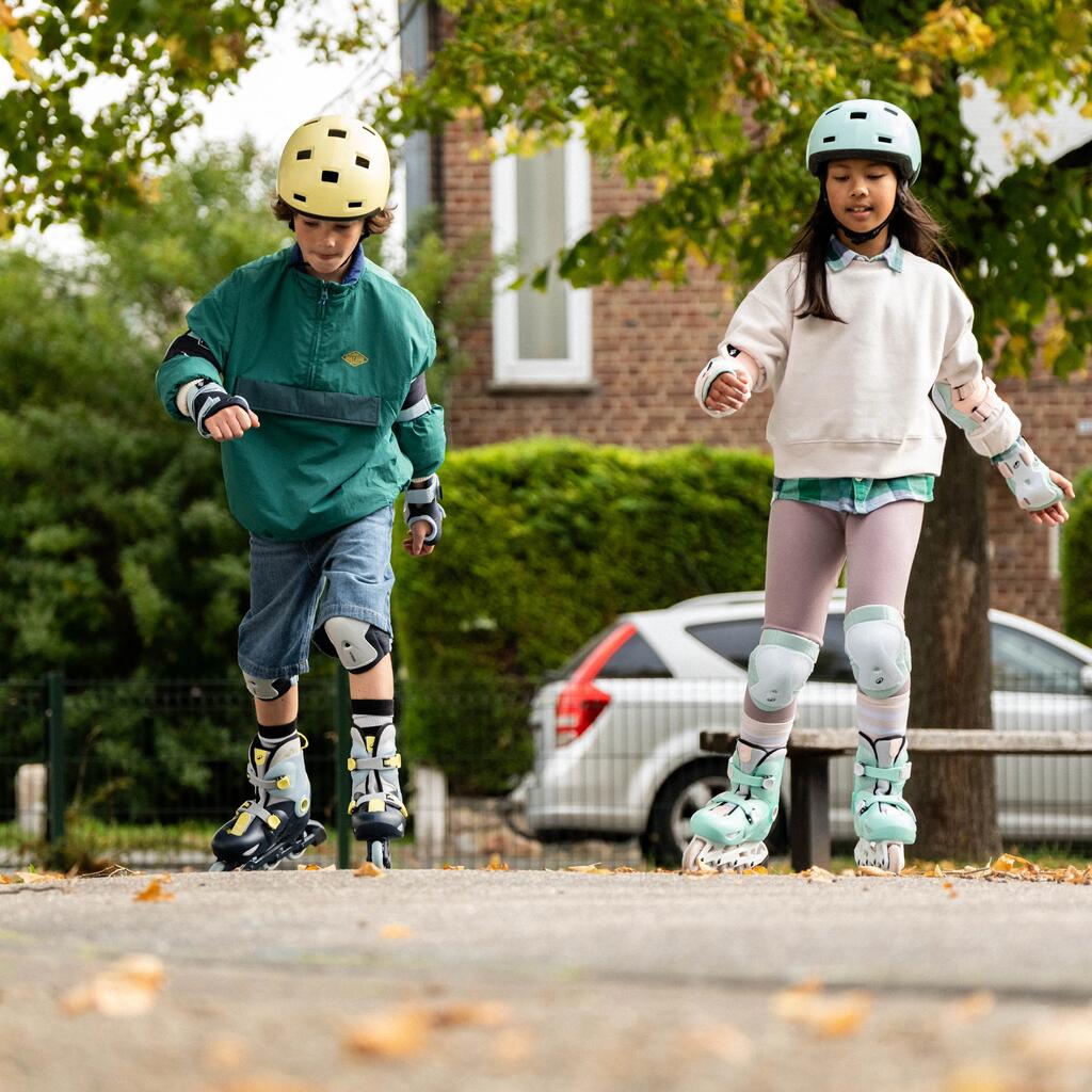 Dvoje dece sa kacigama i kompletnom zaštitnom opremom veselo vozi Oxelo rolere.