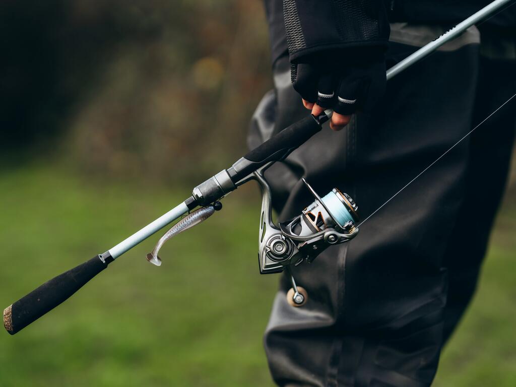 NAhaufnahme einer Angelrute & Rolle in den Händen eines Anglers am Wasser