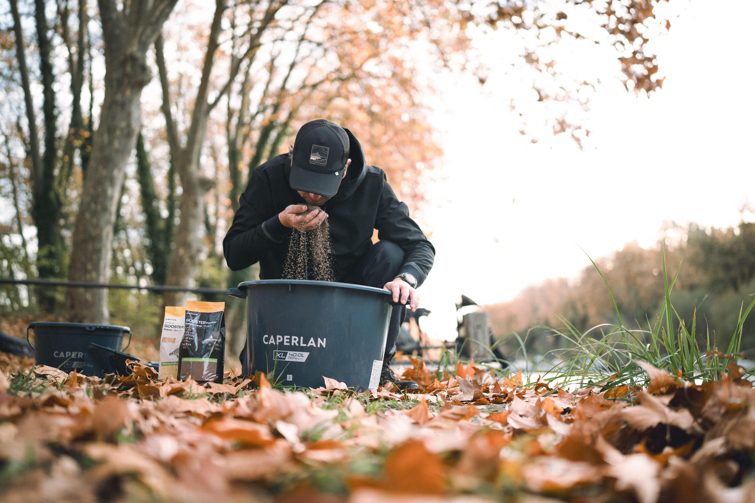 Angler der sich gerade Grundfutter in einem EImer zusammenmischt und daran riecht