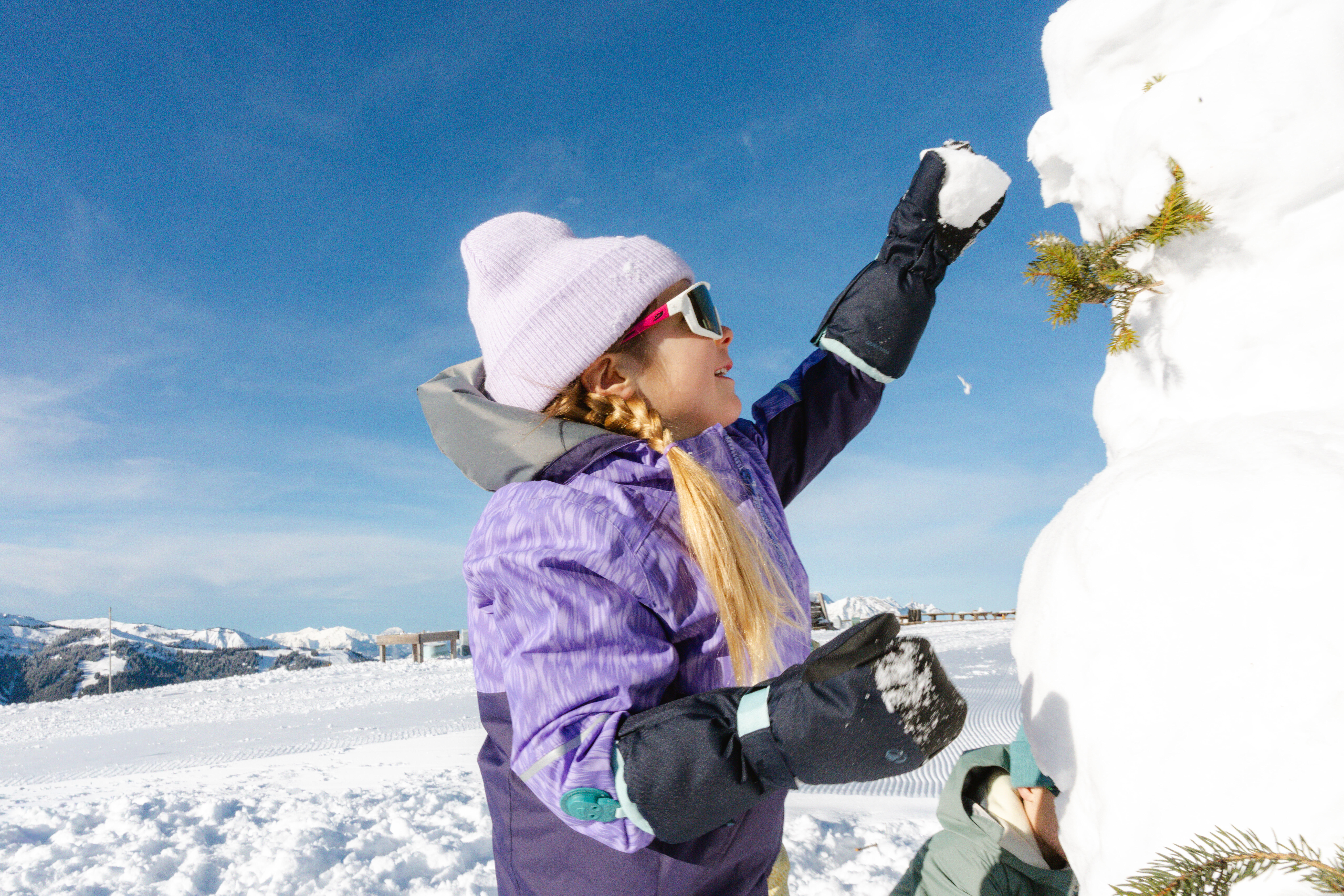 Child wearing black mittens while playing in the snow