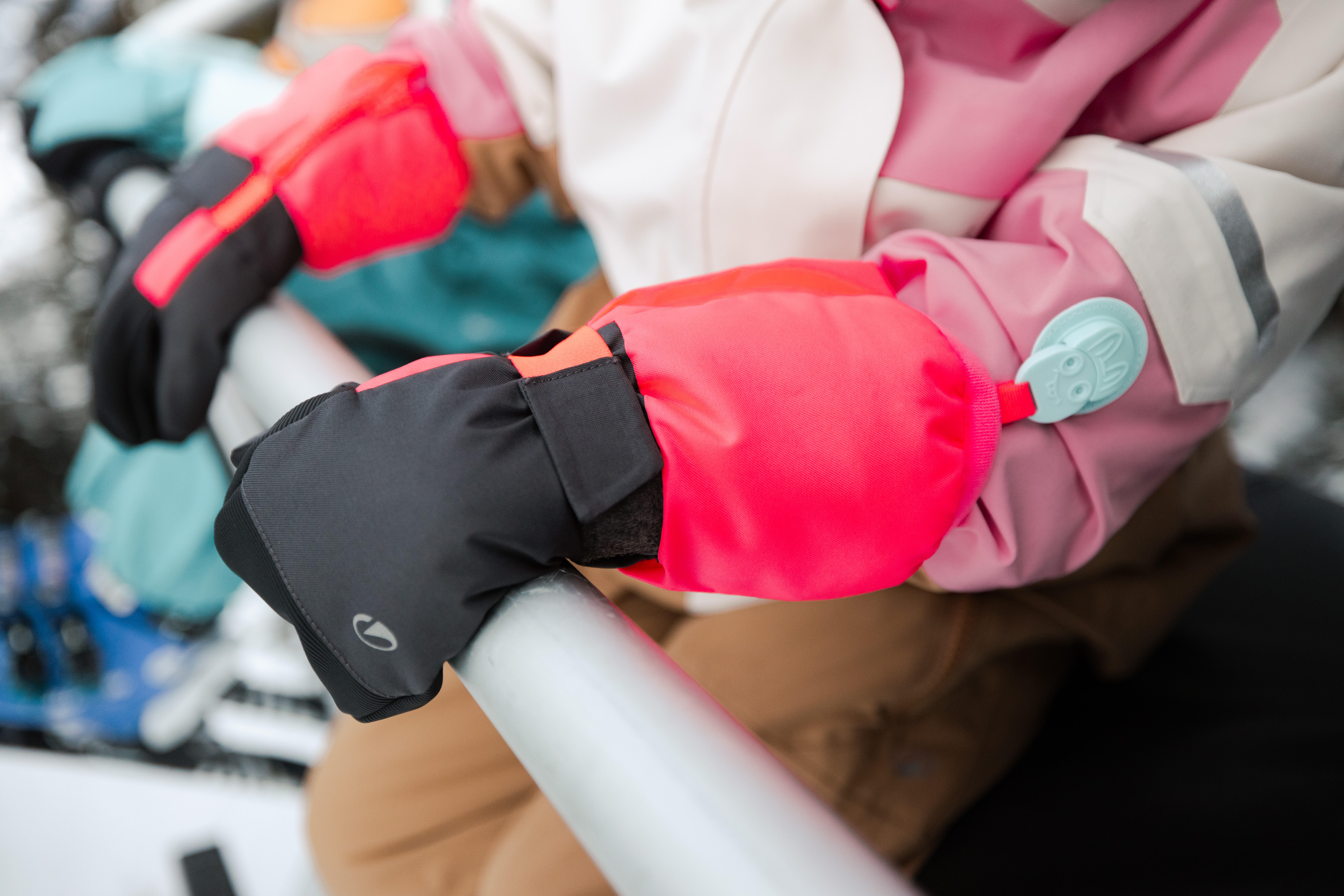 Close-up of children wearing colourful mittens in the snow