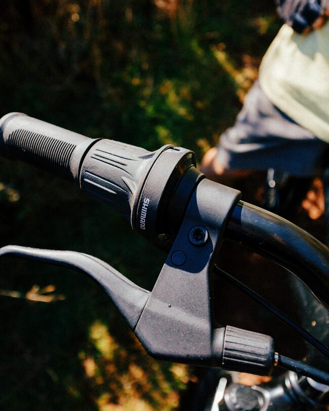 KInd mit schwarzem Helm fährt mit schwarzem Fahrrad auf schlammigem Waldweg