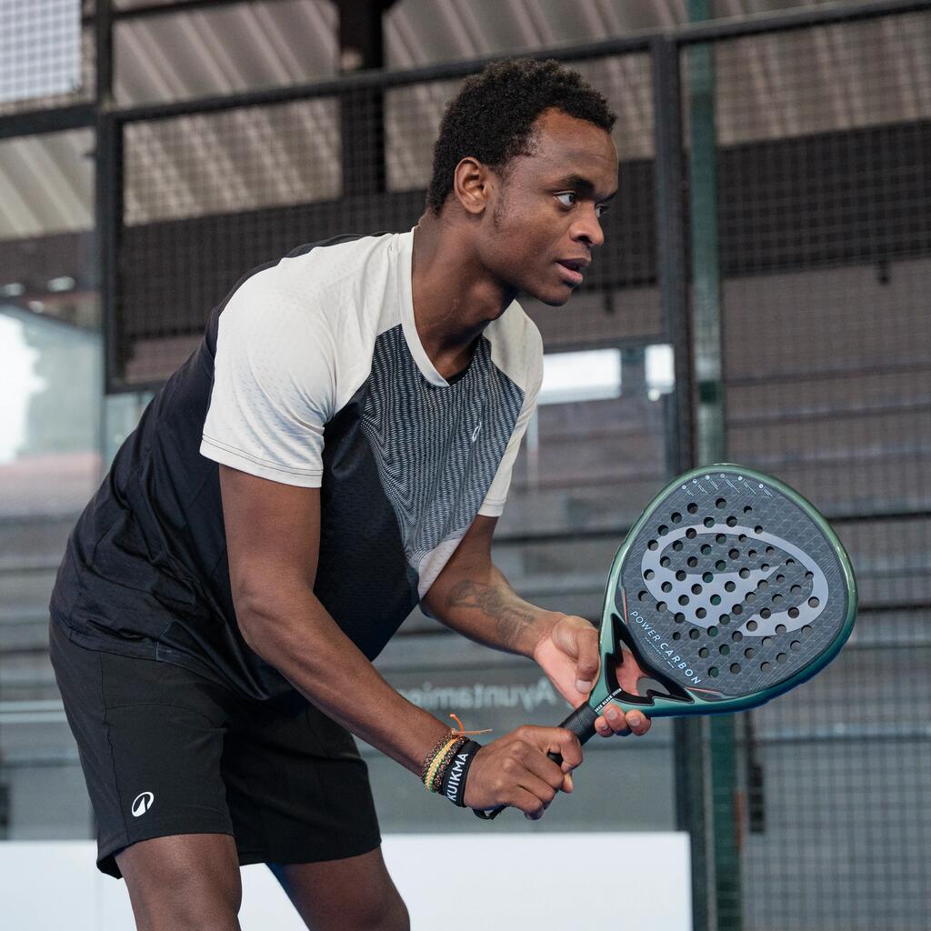Ein Mann hält auf einem Padel-Court konzentriert einen Kuikma-Padelschläger in Beidhändhaltung bereit.
