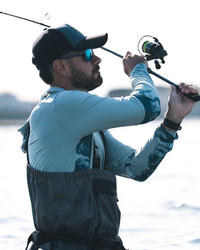 Angler steht im Wasser und wirft gerade seine Rute aus