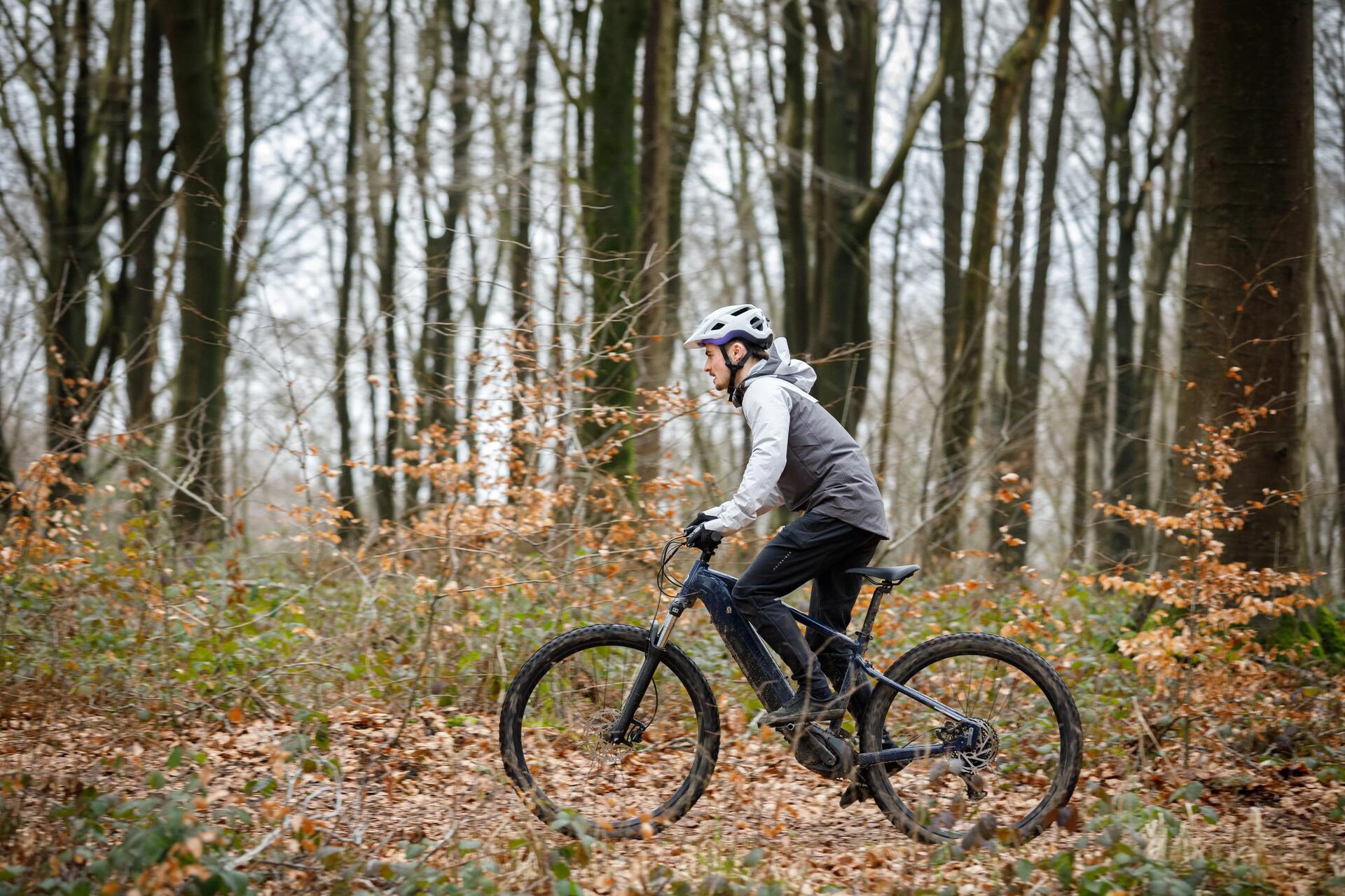 Mężczyzna w kasku jadący rowerem elektrycznym mtb w lesie