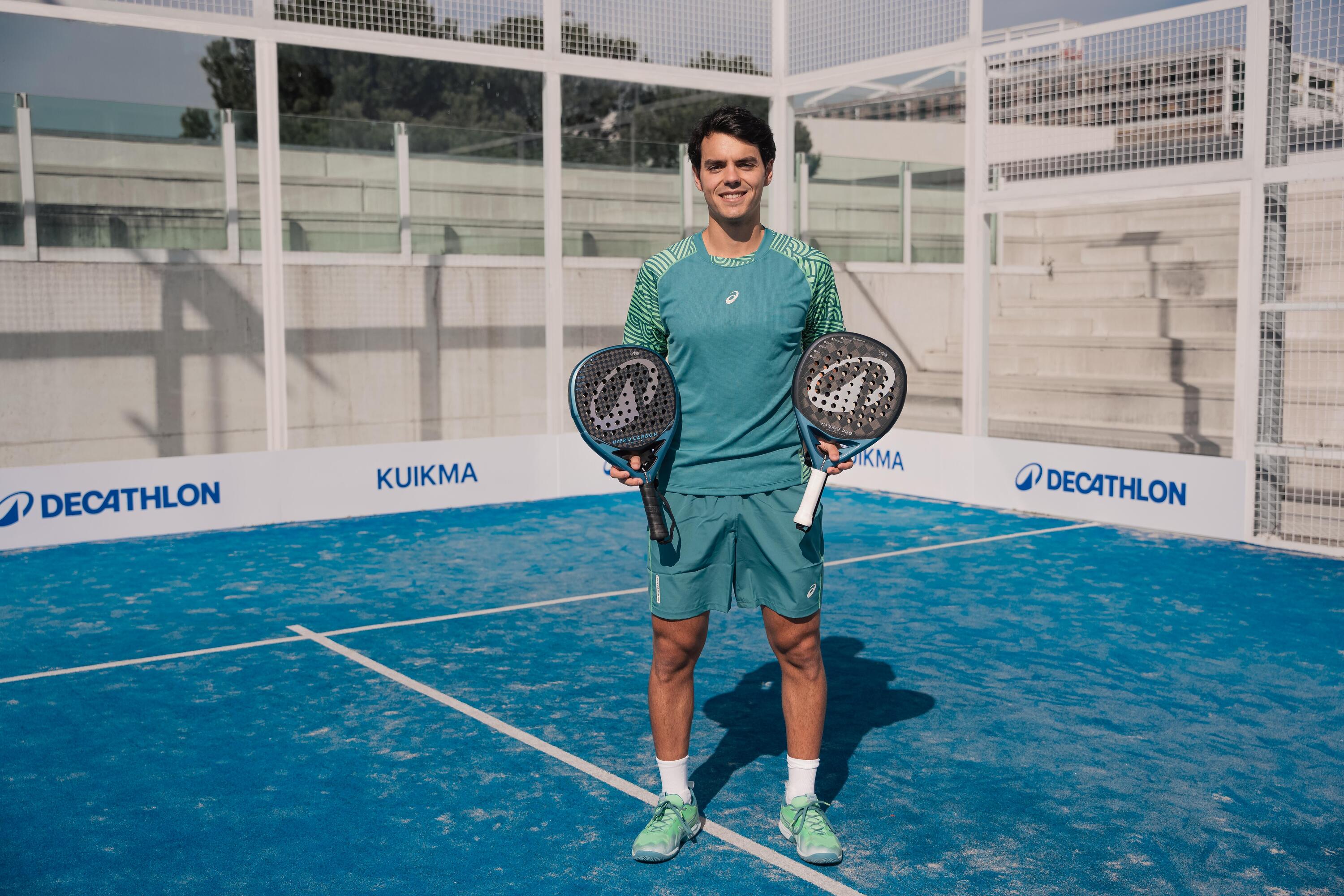 Cokie Nieto auf einem blauen Padelcourt mit zwei Kuikma Padelschlägern in der Hand, die er präsentiert.