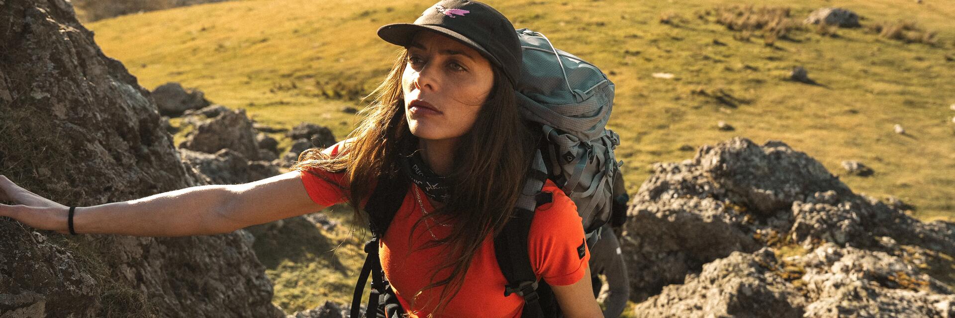 Kobieta w czapce z daszkiem z plecakiem trekkingowym wędrująca po górach