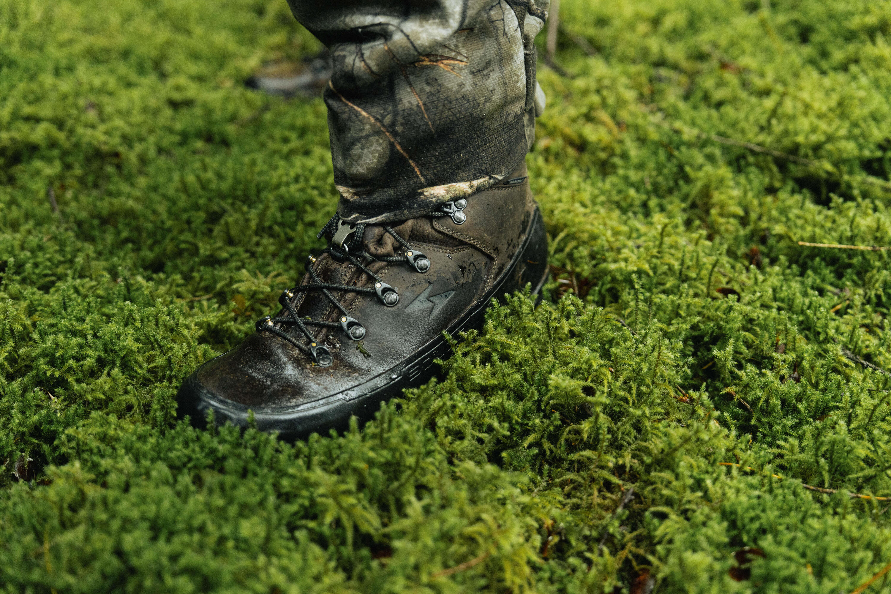 Chasseur avec les chaussures Crosshunt 900 aux pieds au milieu d'une végétation avec de la mousse 