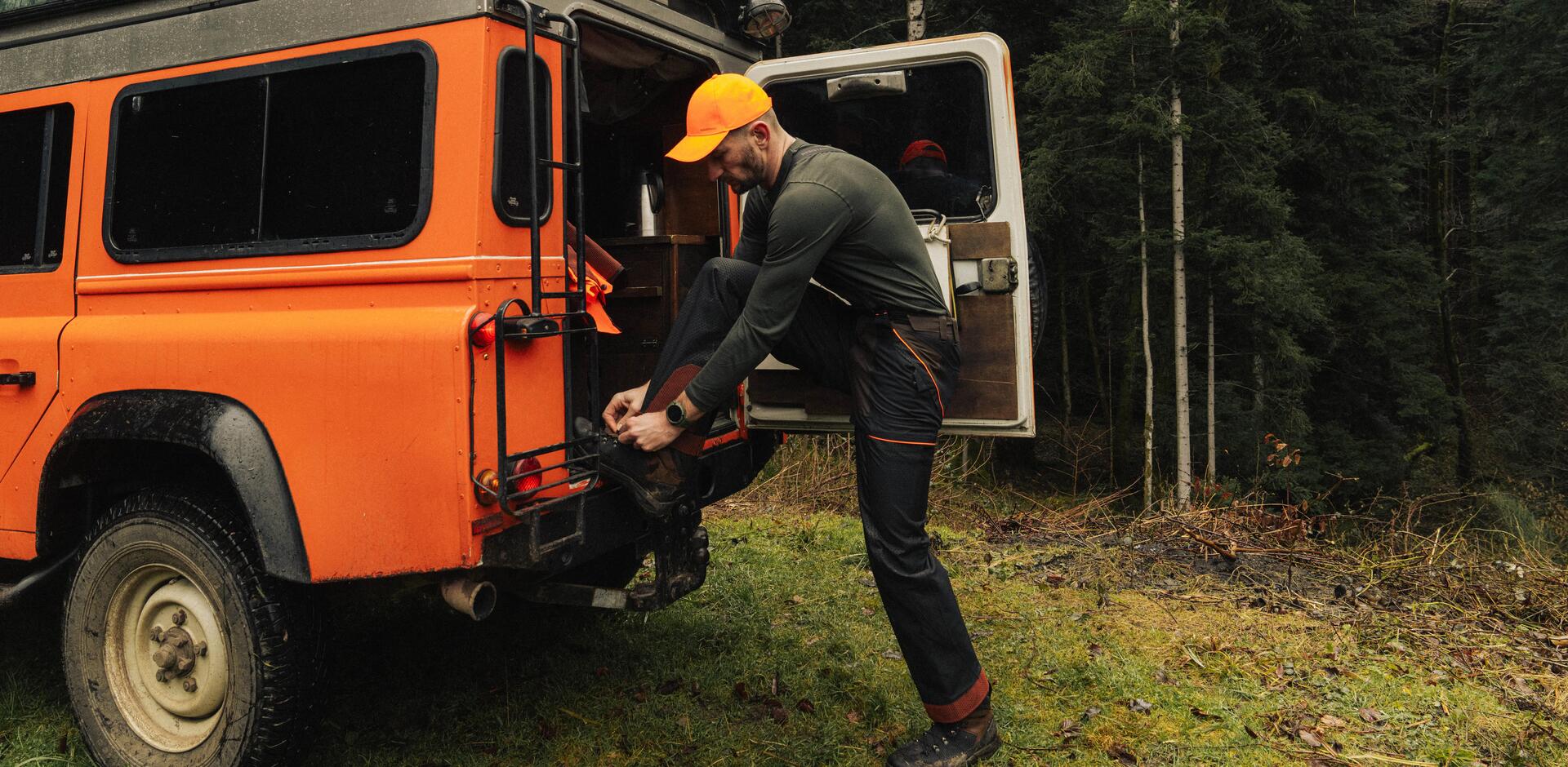 un chasseur se prépare et lace ses chaussures au cul de sa voiture
