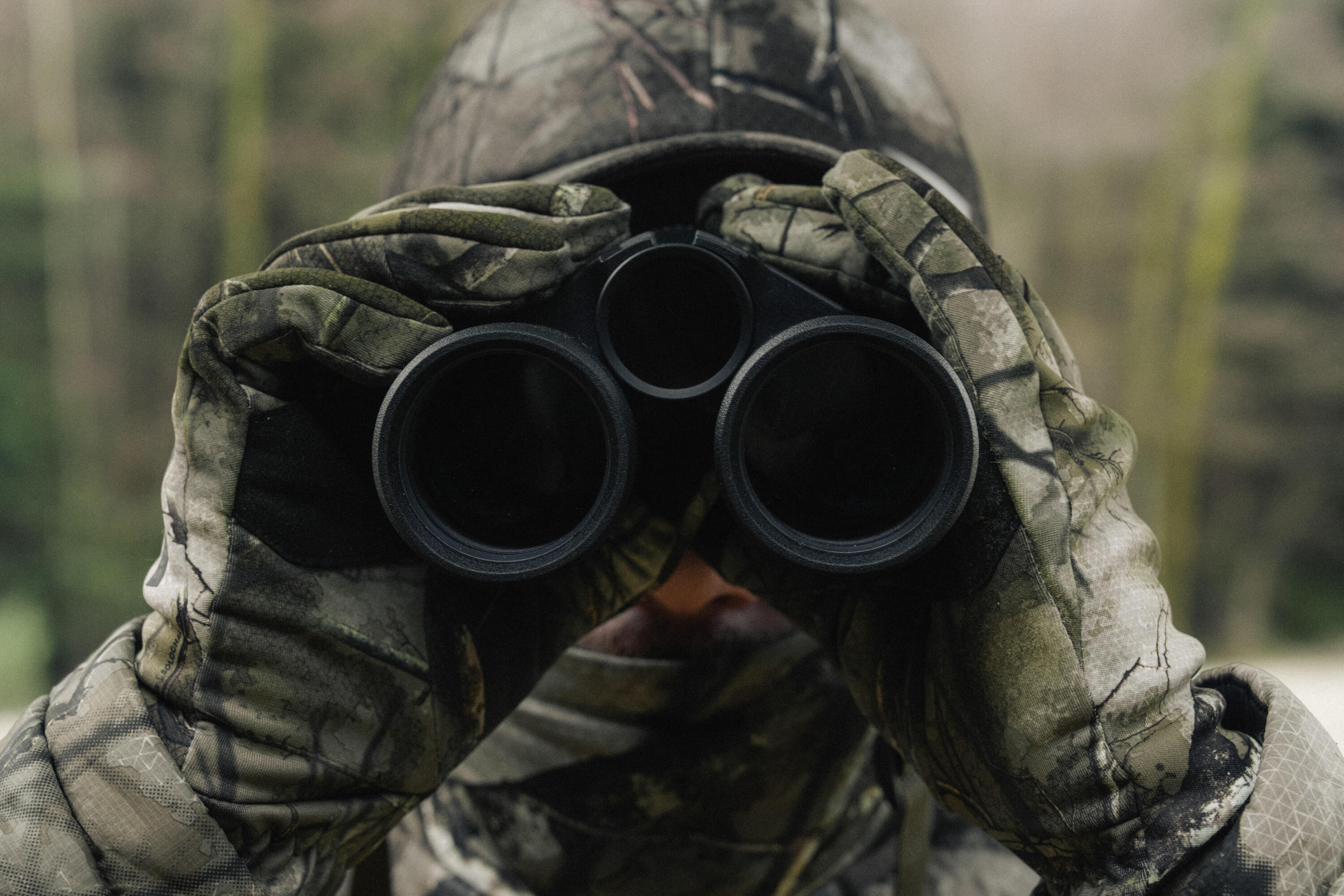 Un chasseur de face qui jumelle avec une paire d'optiques Solognac