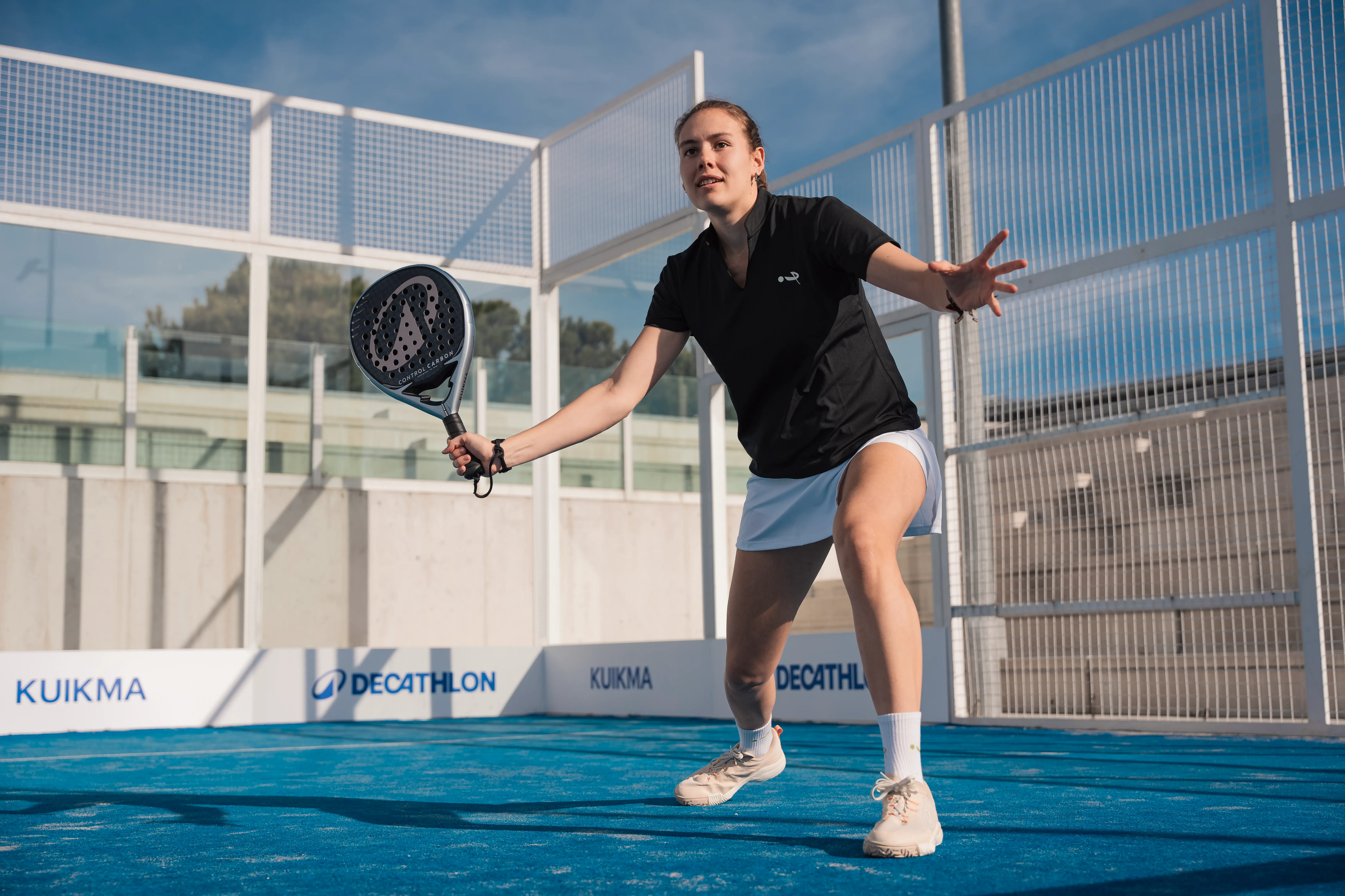 Eine Frau, die auf einem Outdoor-Court Padel spielt.