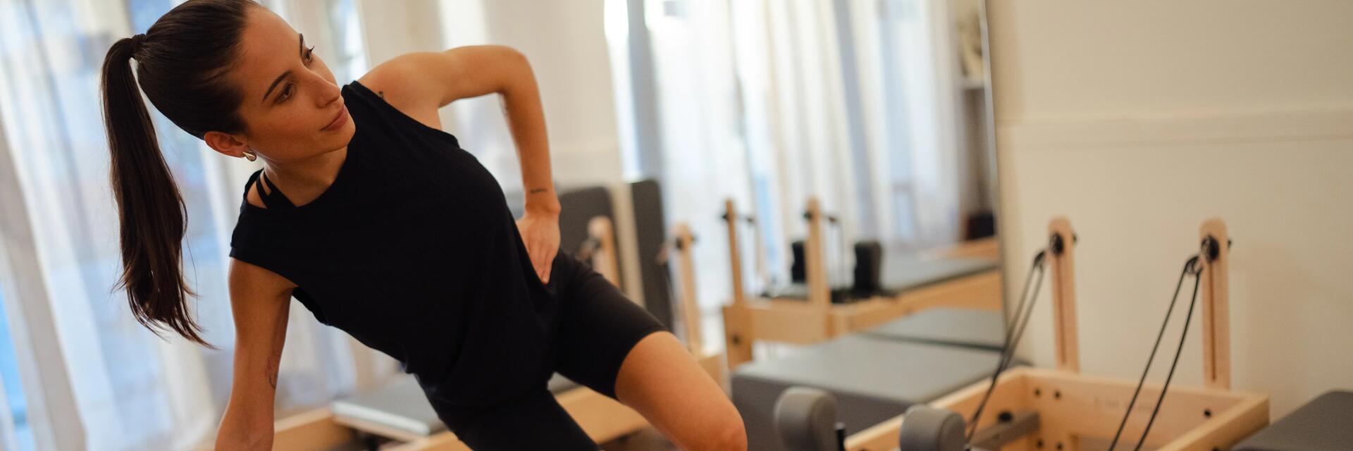 Kobieta w odzieży do pilatesu trenująca pilates na reformerze