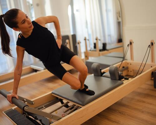 Kobieta w odzieży do pilatesu trenująca pilates na reformerze