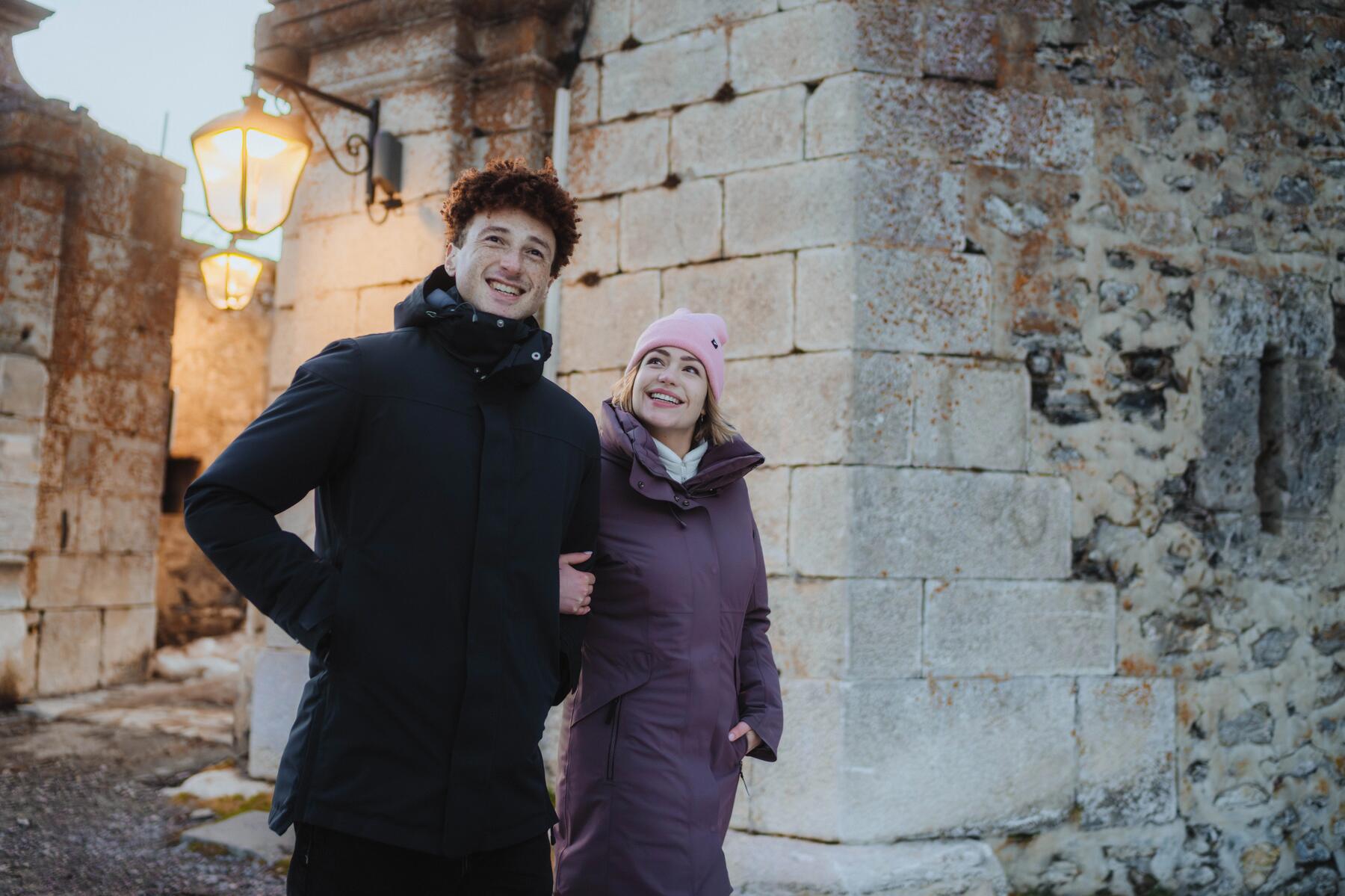 couple H/F qui se balade dans une ville de type médiévale, ils sourient