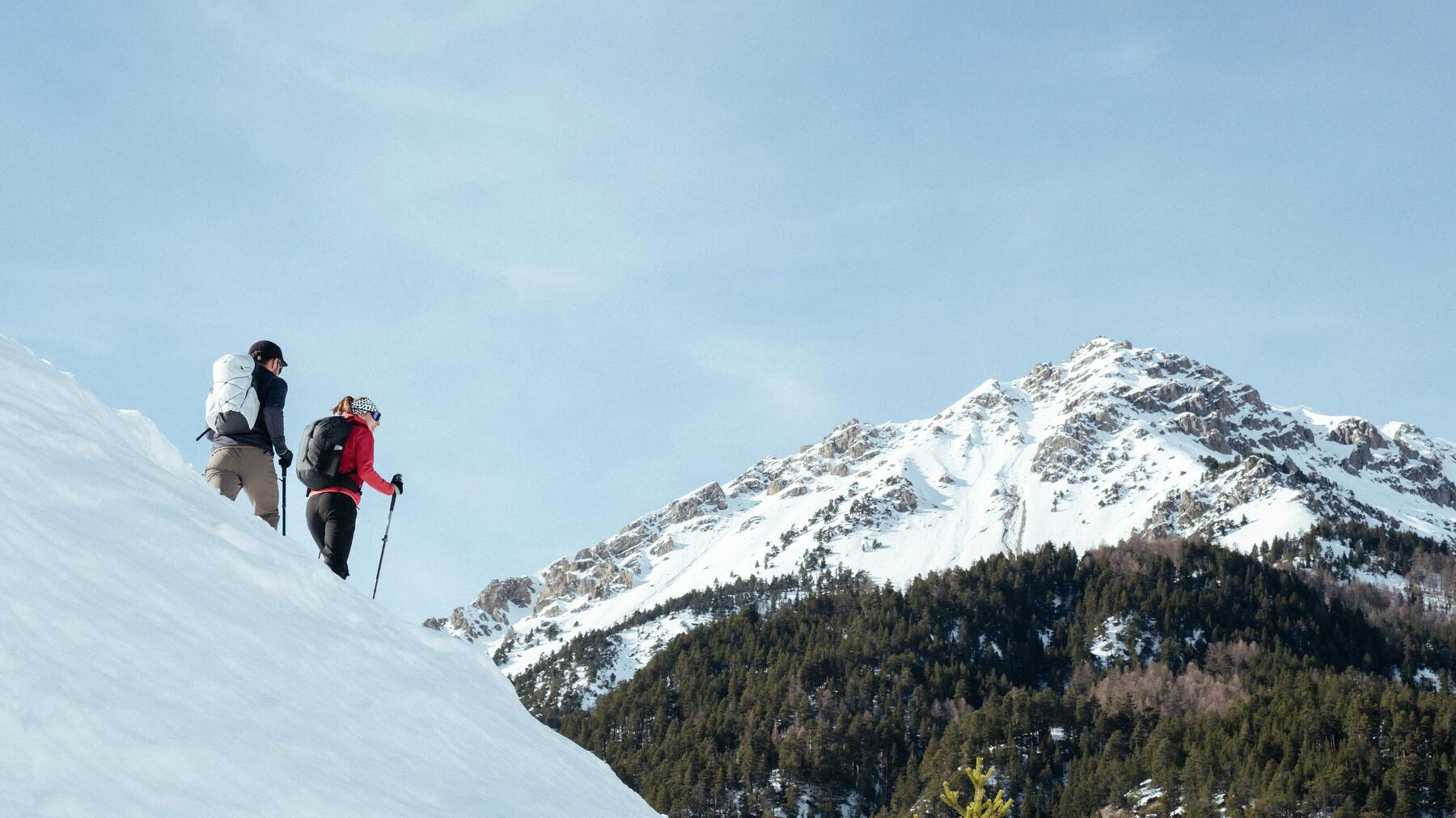 Zwei Wanderer auf verschneitem Wanderweg mitsamt ihrer Wanderaustüstung