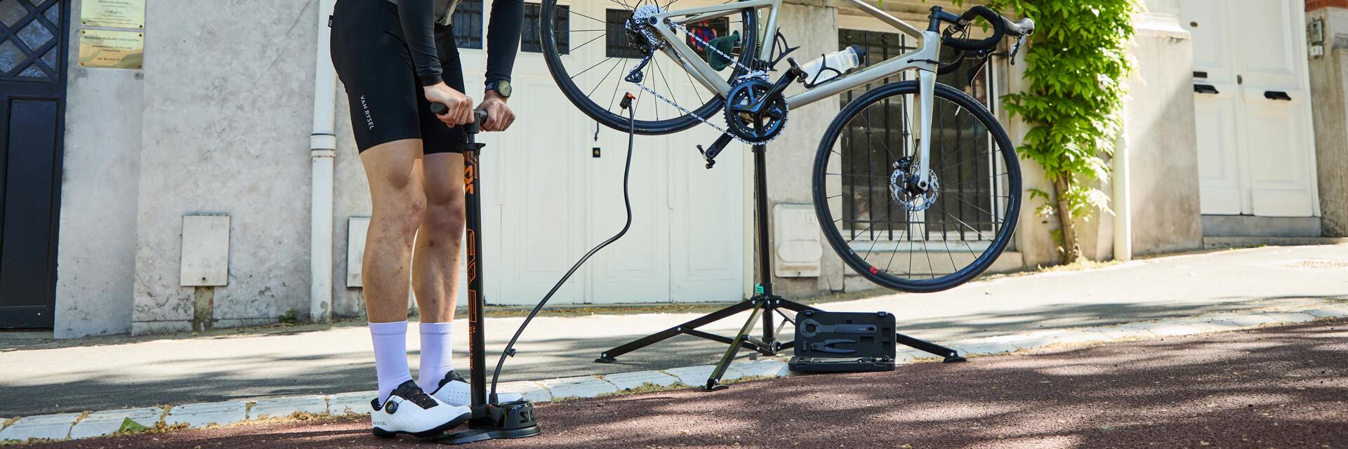Ein Mann steht auf der Straße und nutzt eine Fahrradpumpe