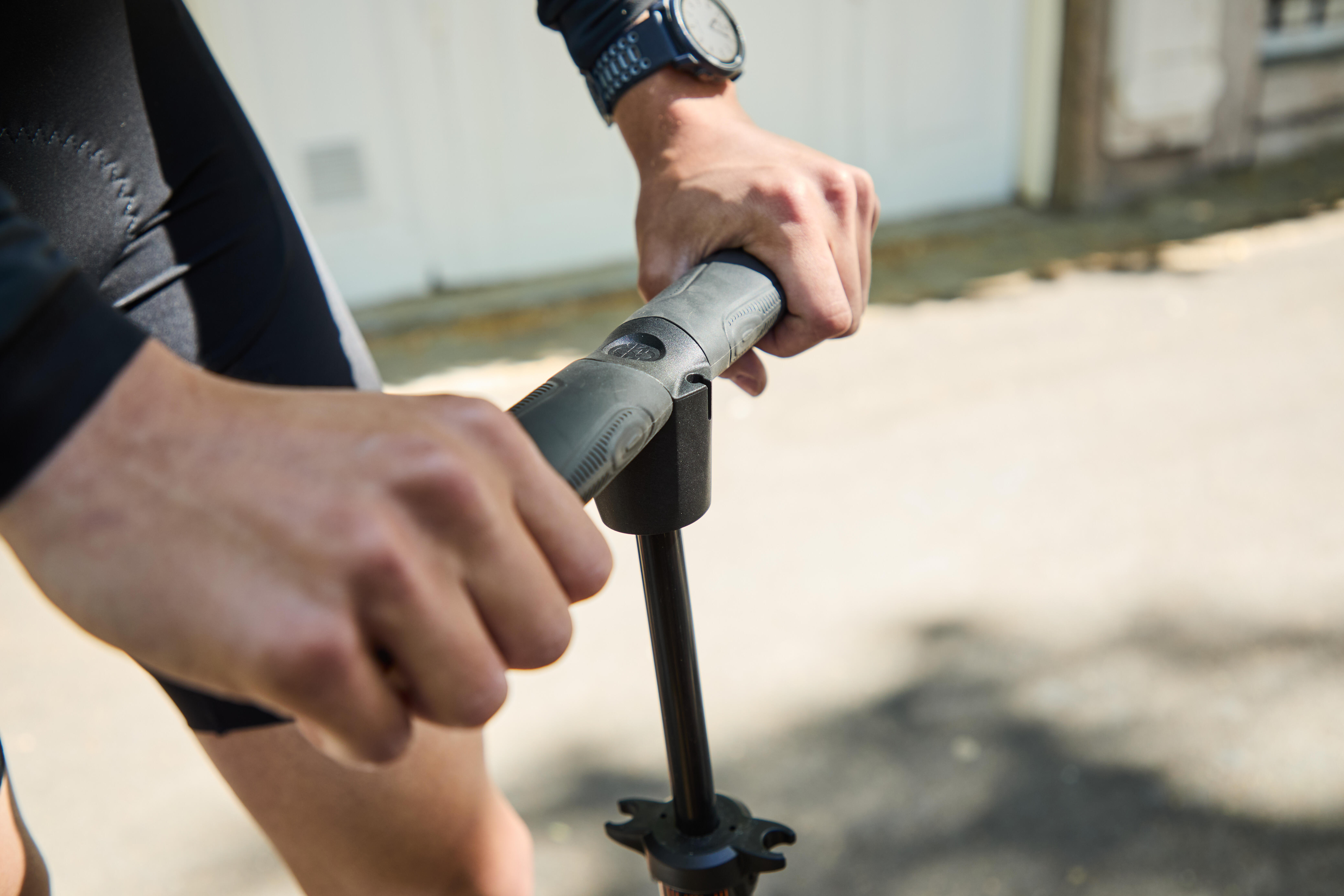 Close-up of a cyclist using the handle of a bicycle floor pump.