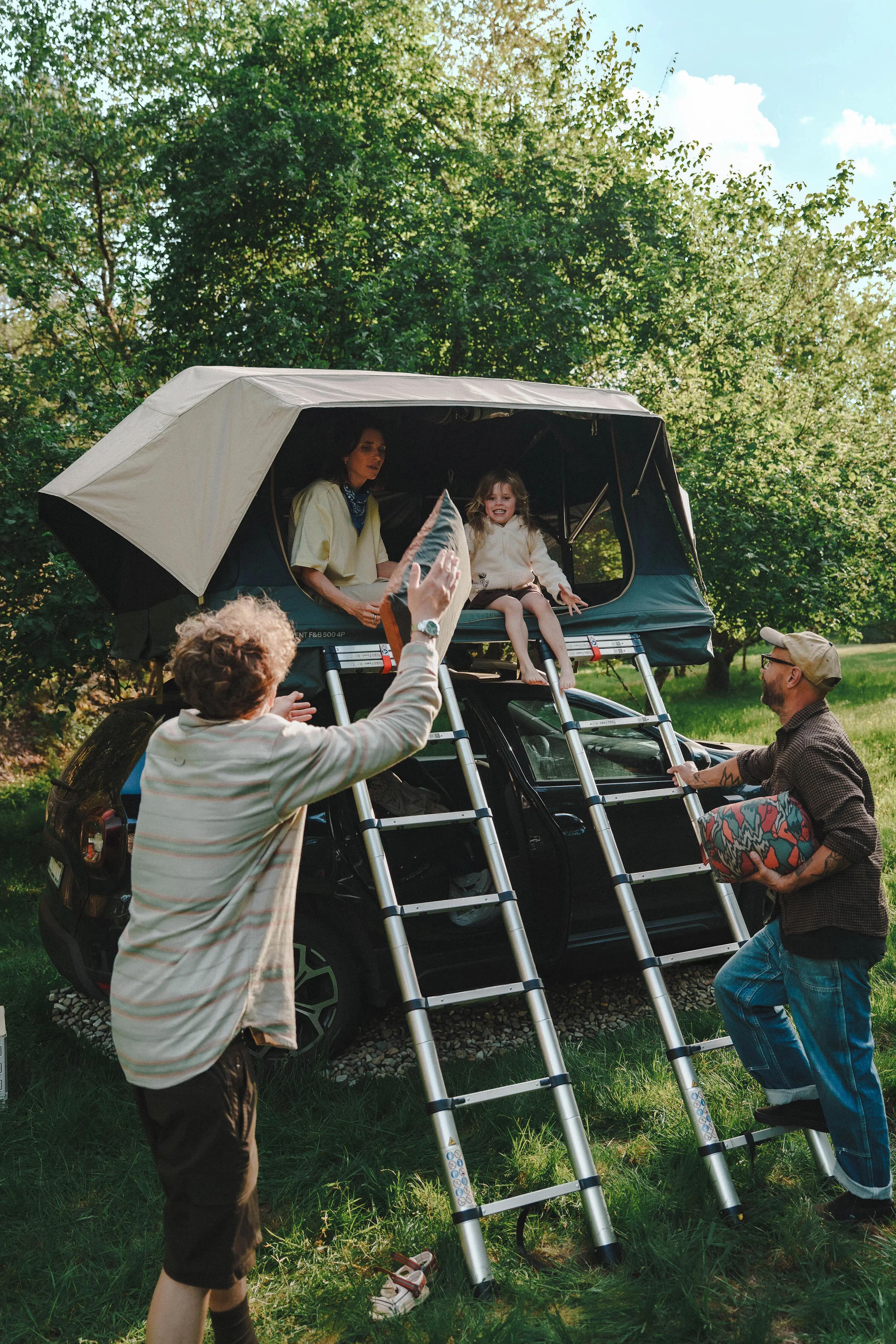 Eine Familie ist mit dem Auto und einem Decathlon Dachzelt beim Campen