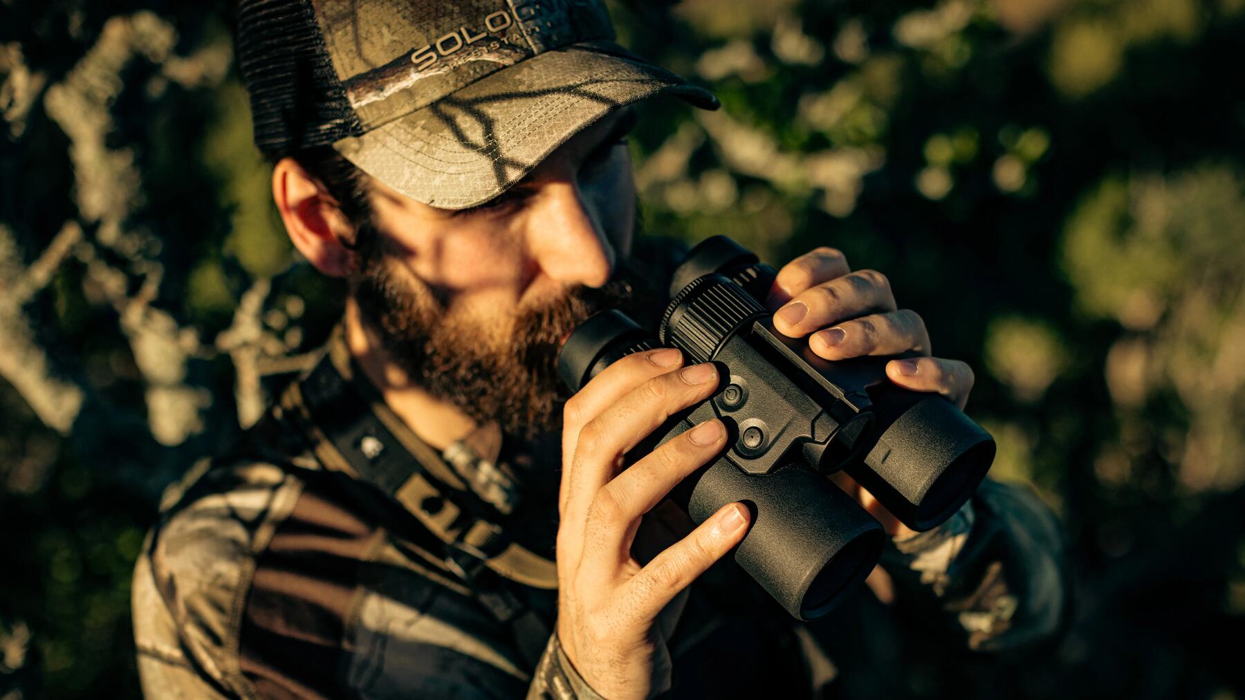Mann mit Fernglas im Wald bei der Jagd