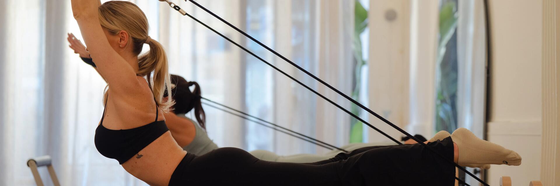 Kobiety ćwiczące pilates na reformerach