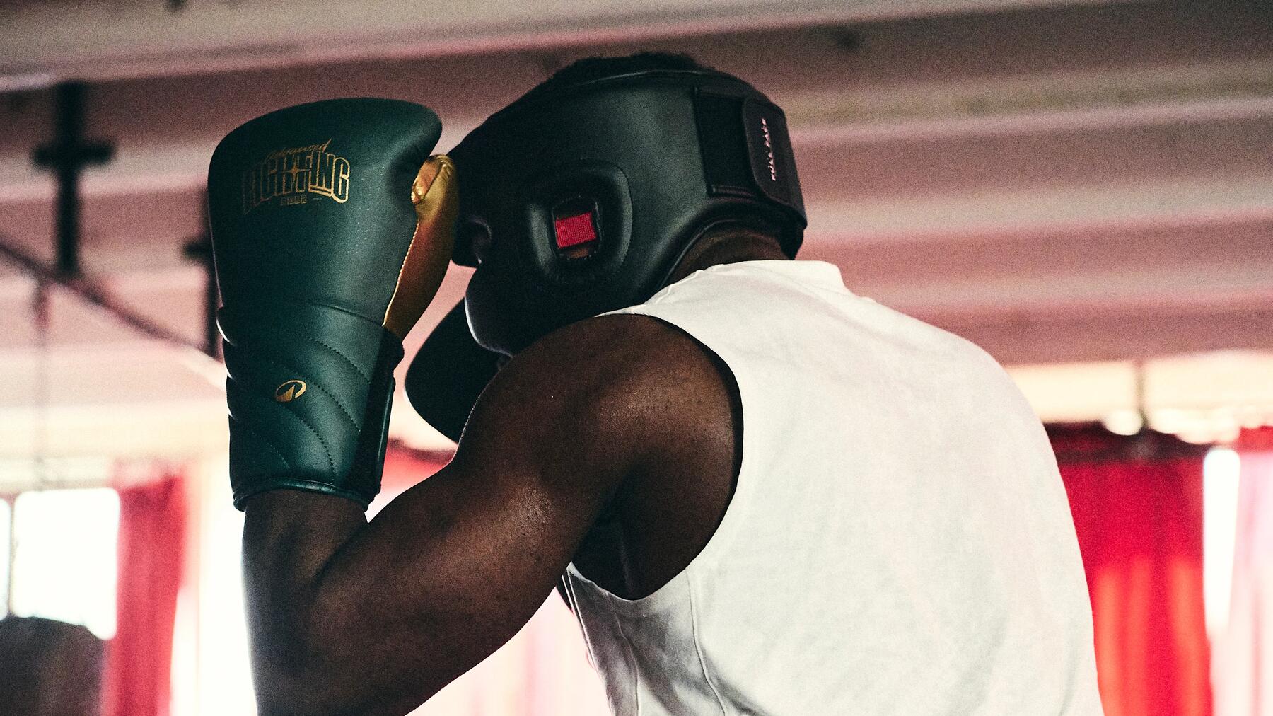 Mężczyzna w kasku i w rękawicach trenujący shadowboxing