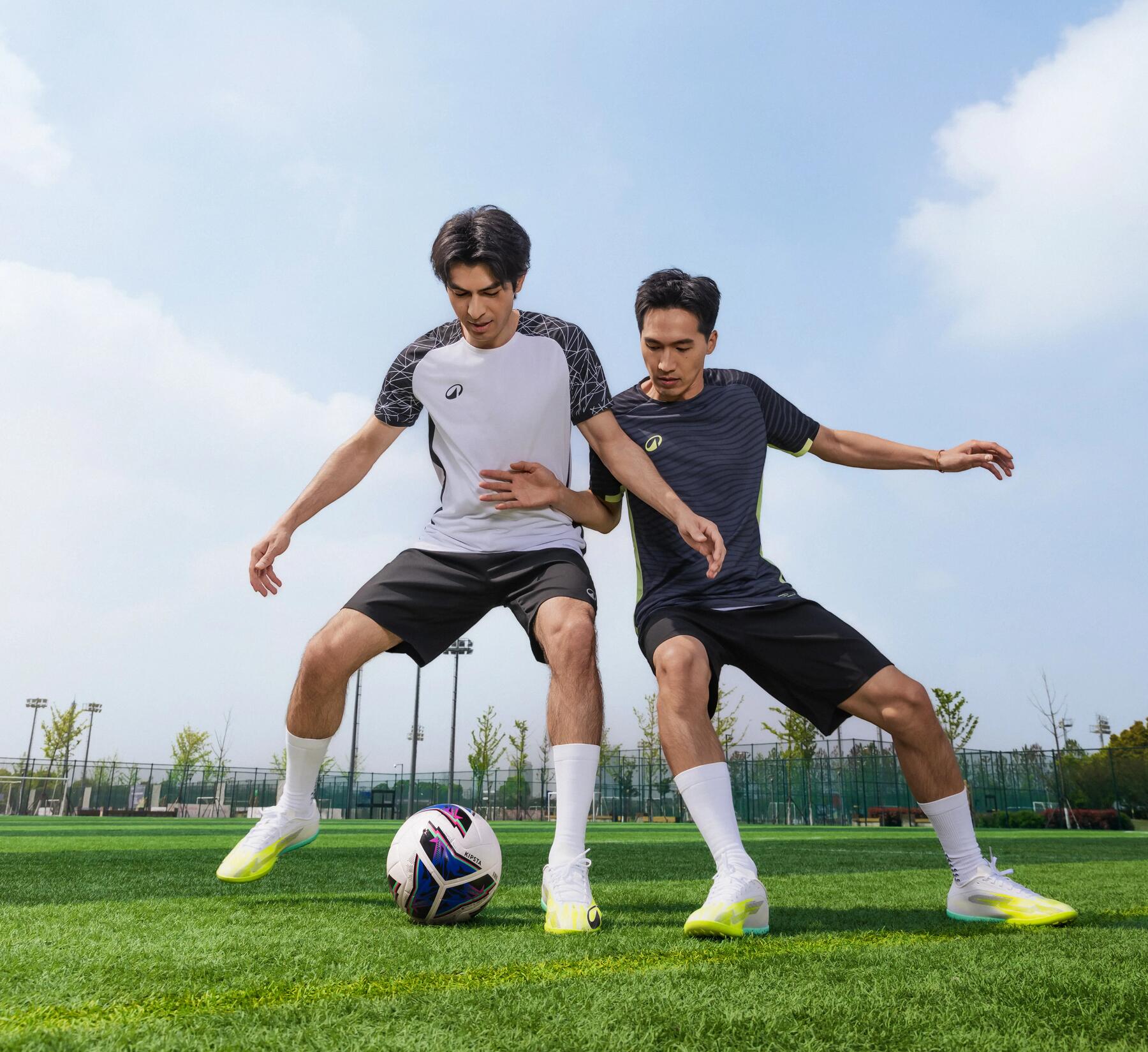 Zwei Personen tragen Fußballkleidung und spielen auf Rasen gegeneinander