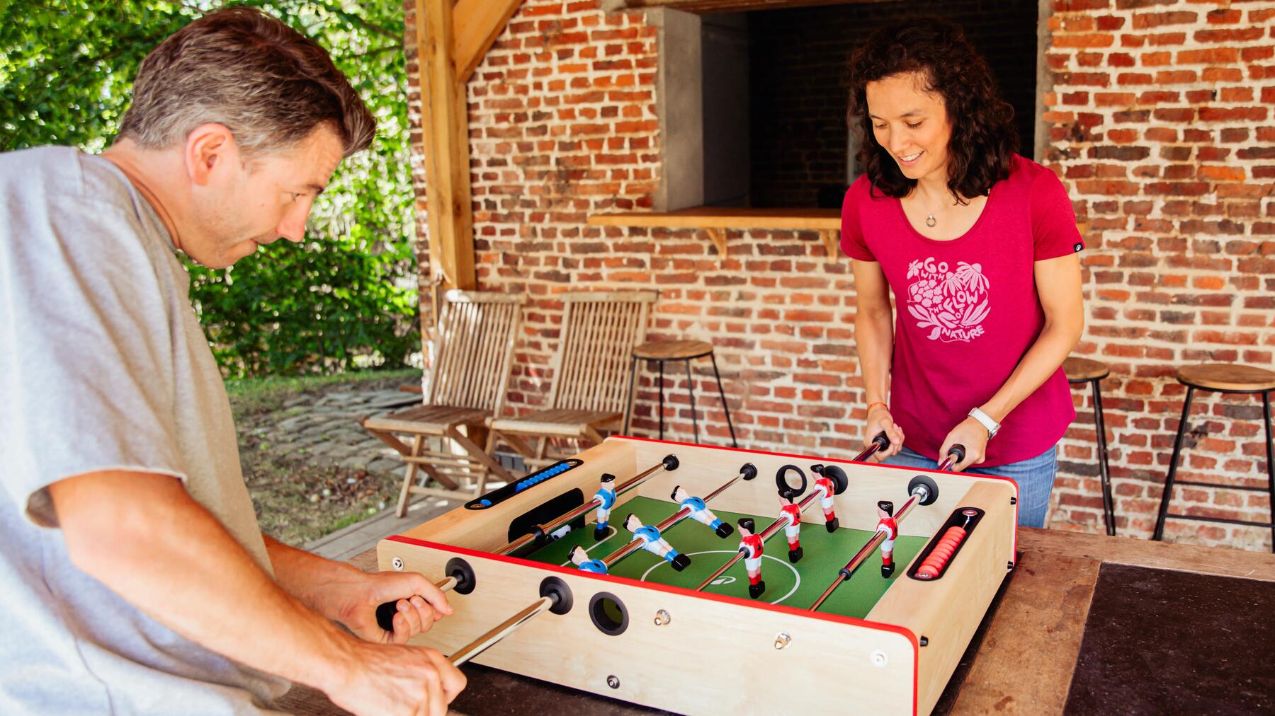 Ein Mann und eine Frau, die mit einem Tischkicker spielen.