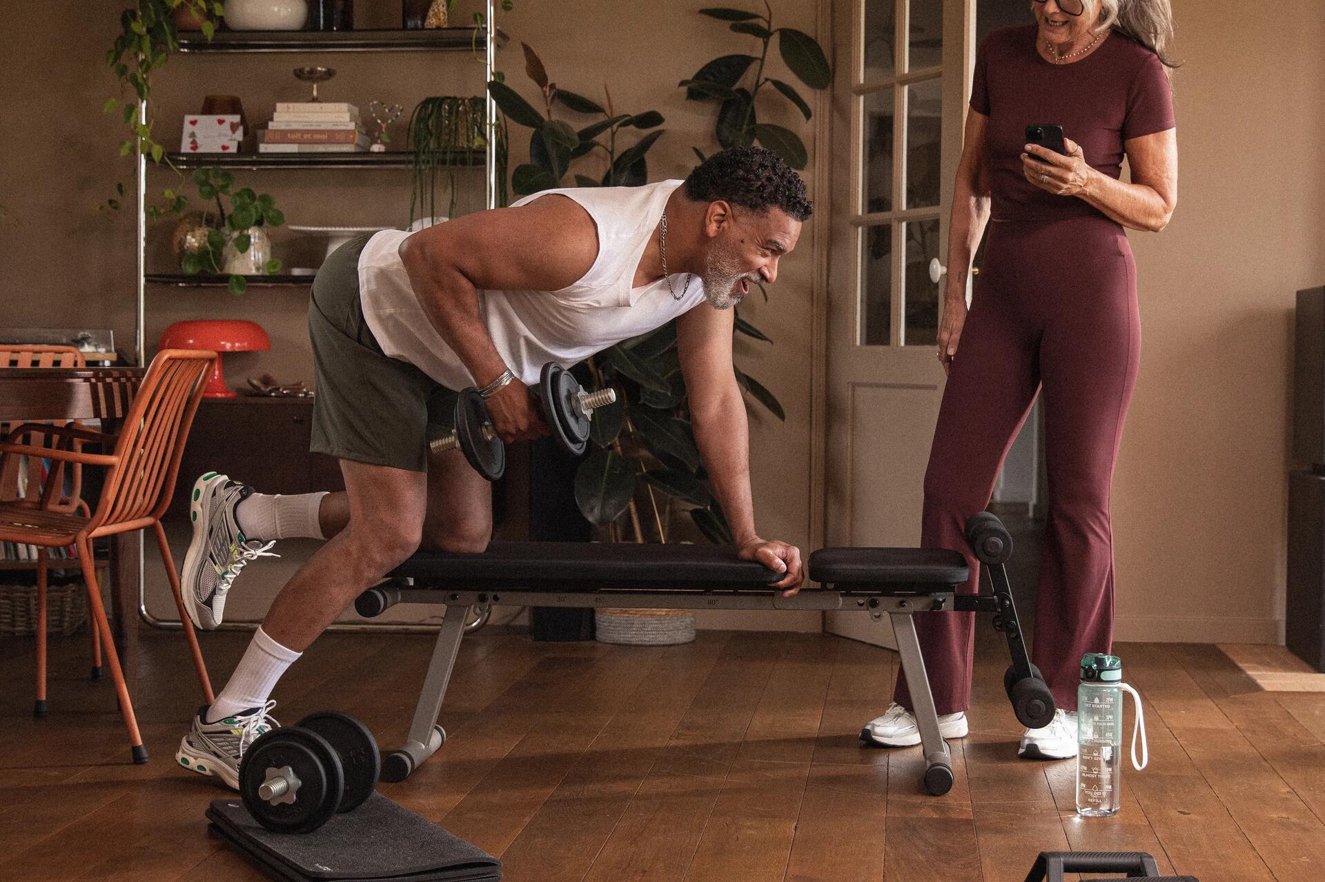 Mężczyzna w spodenkach i butach fitness trenujący z hantlami wykorzystując etap superkompensacji