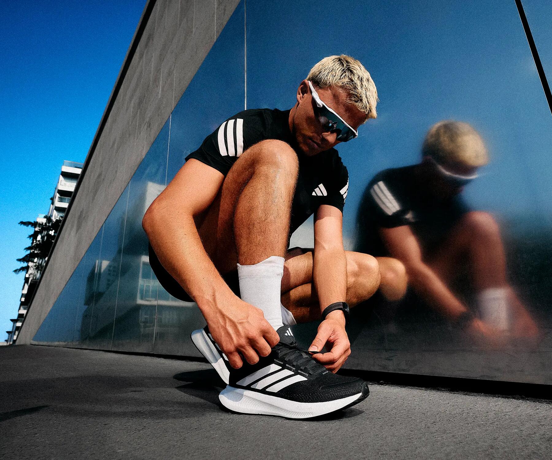 Ein Mann in Kleidung zum Cardiotraining macht sich die Schuhe zu
