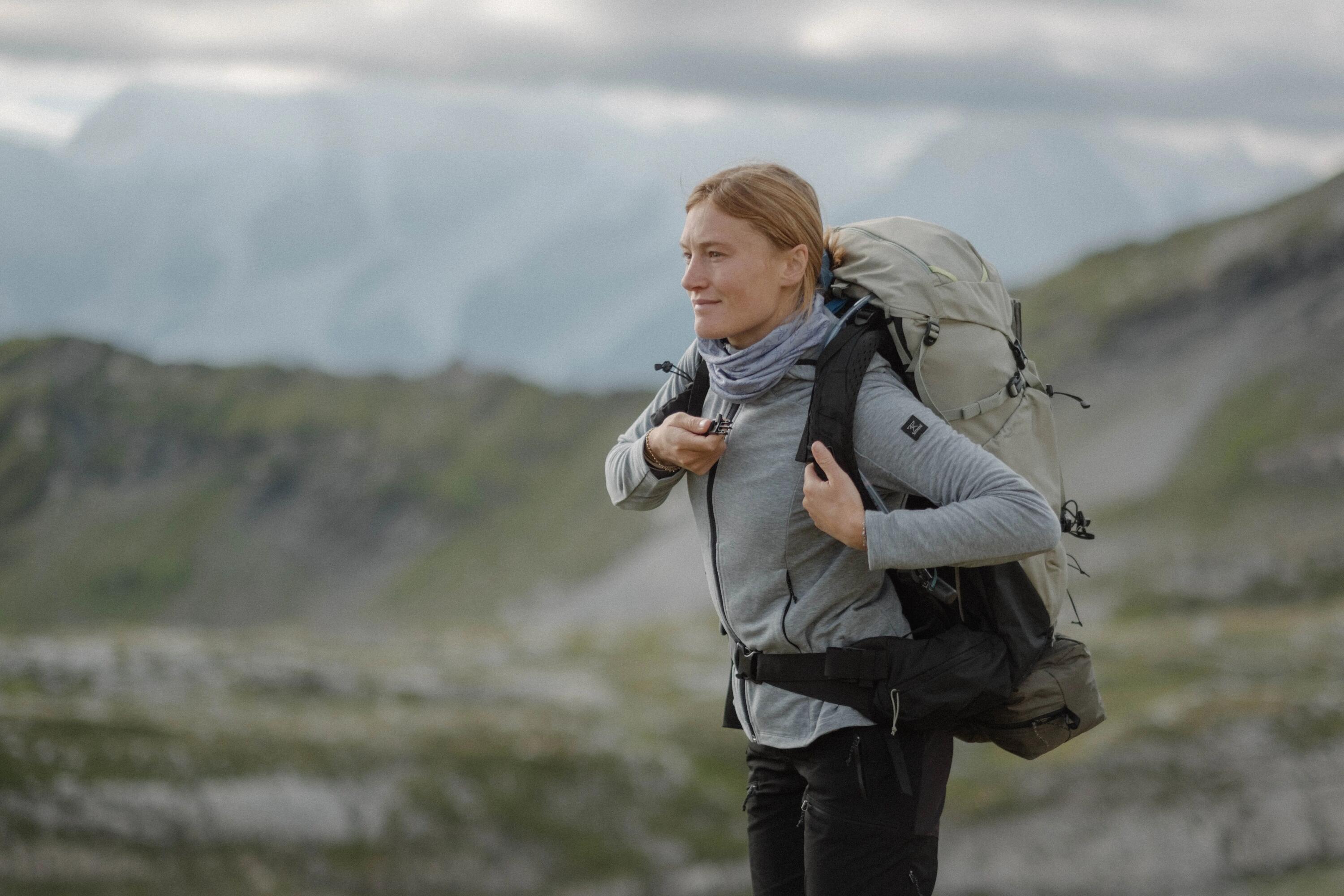 Frau steht im Vordergrund mit Berglandschaft im Hintergrund
