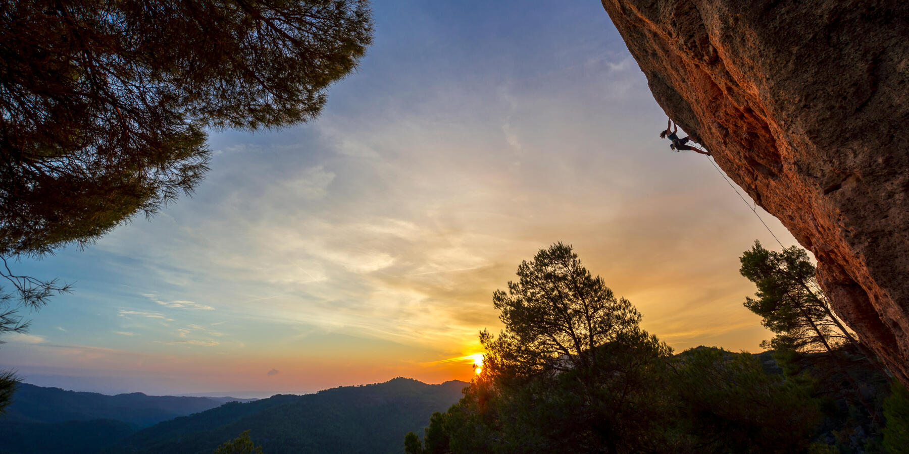 coucher de soleil avec un grimpeur sur une paroi rocheuse