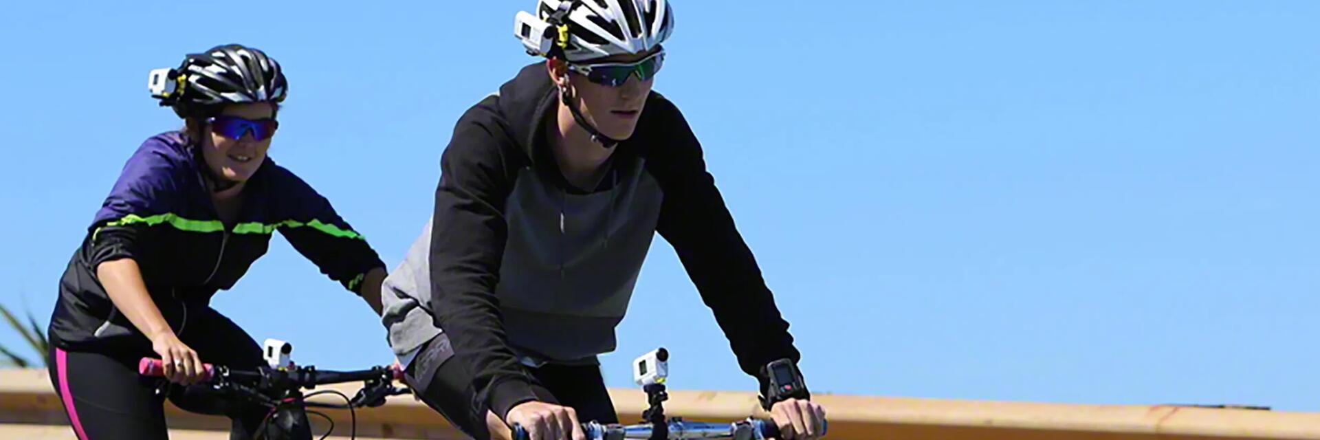 Osoby jadące na rowerach z kamerami rowerowymi zamocowanymi na kaskach i kierownicach rowerowych