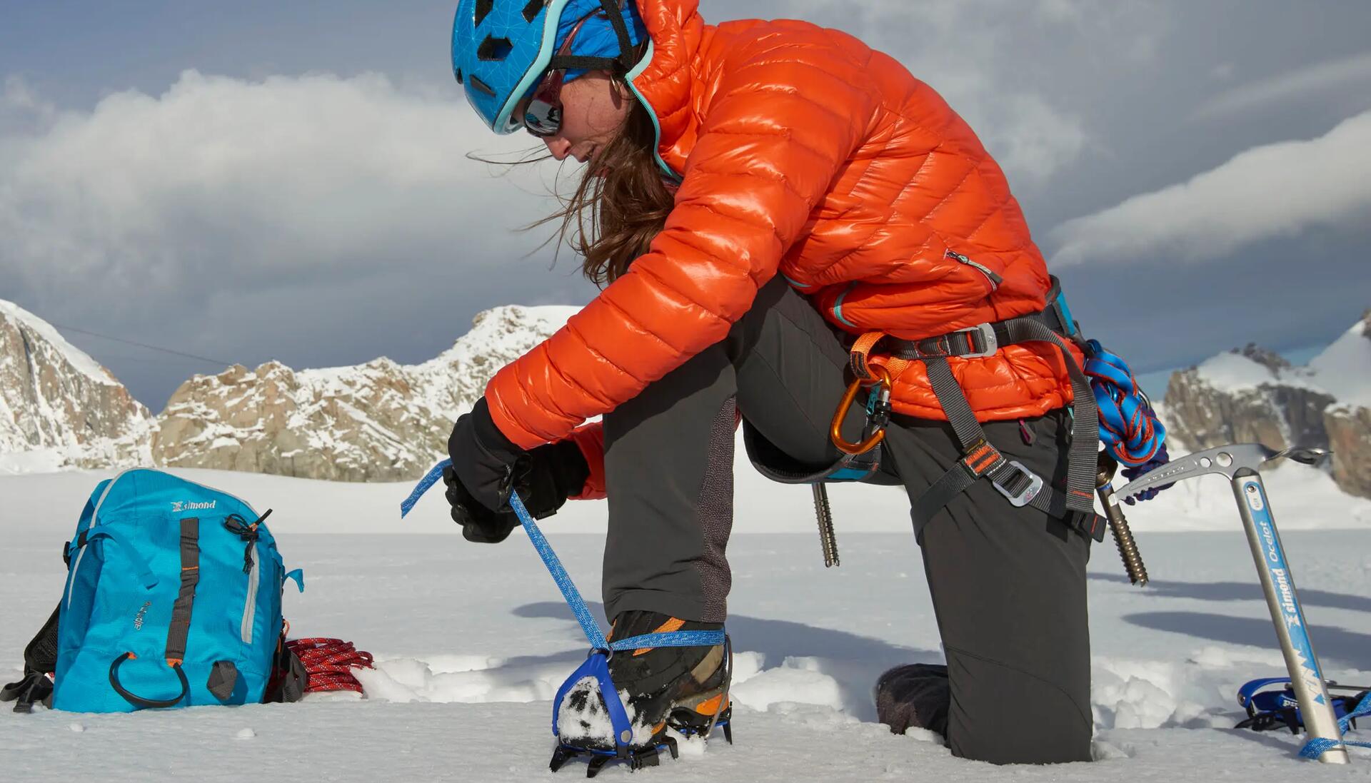kobieta w kasku do wspinaczki zakładająca raki na buty alpinistyczne
