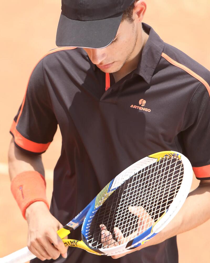 Ein Tennisspieler betrachtet seinen Tennisschläger