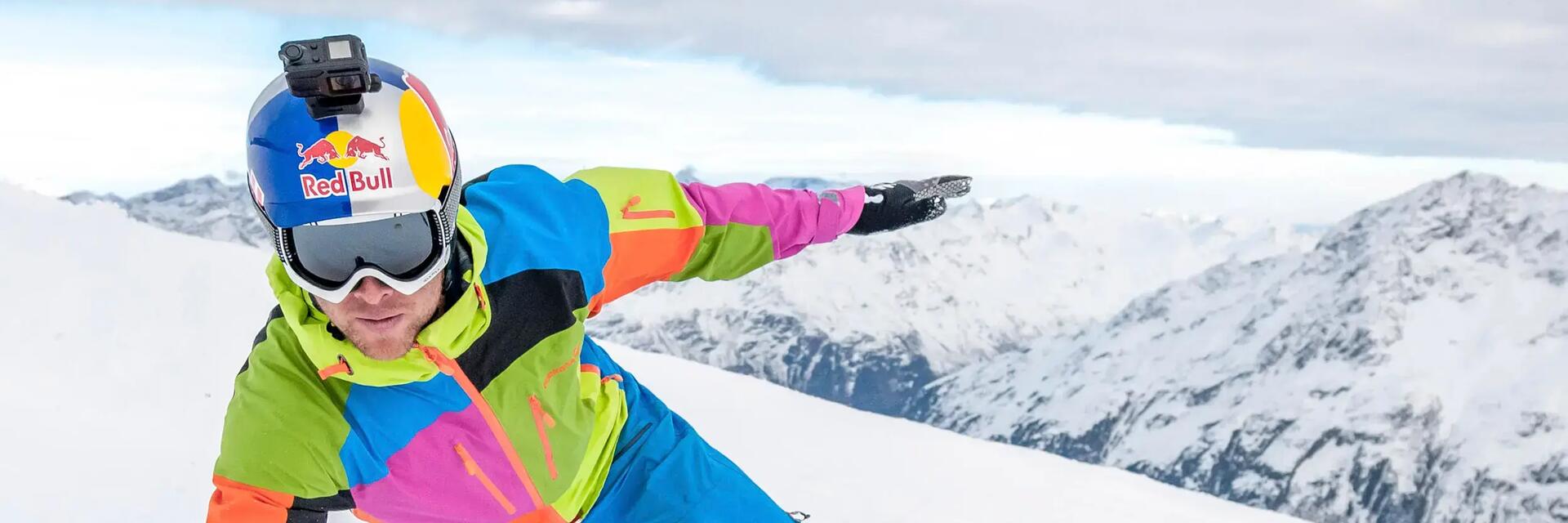Mężczyzna w kasku narciarskim z zamontowaną kamerą GoPro jeżdżacy na snowboardzie