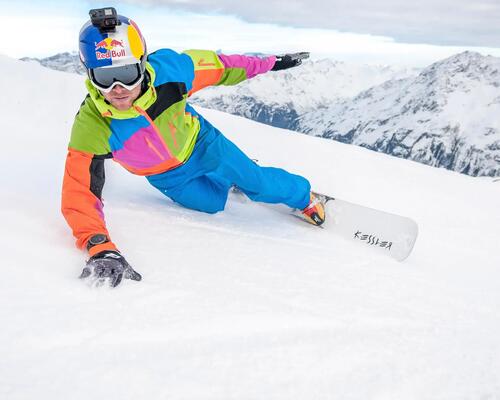 Mężczyzna w kasku narciarskim z zamontowaną kamerą GoPro jeżdżacy na snowboardzie