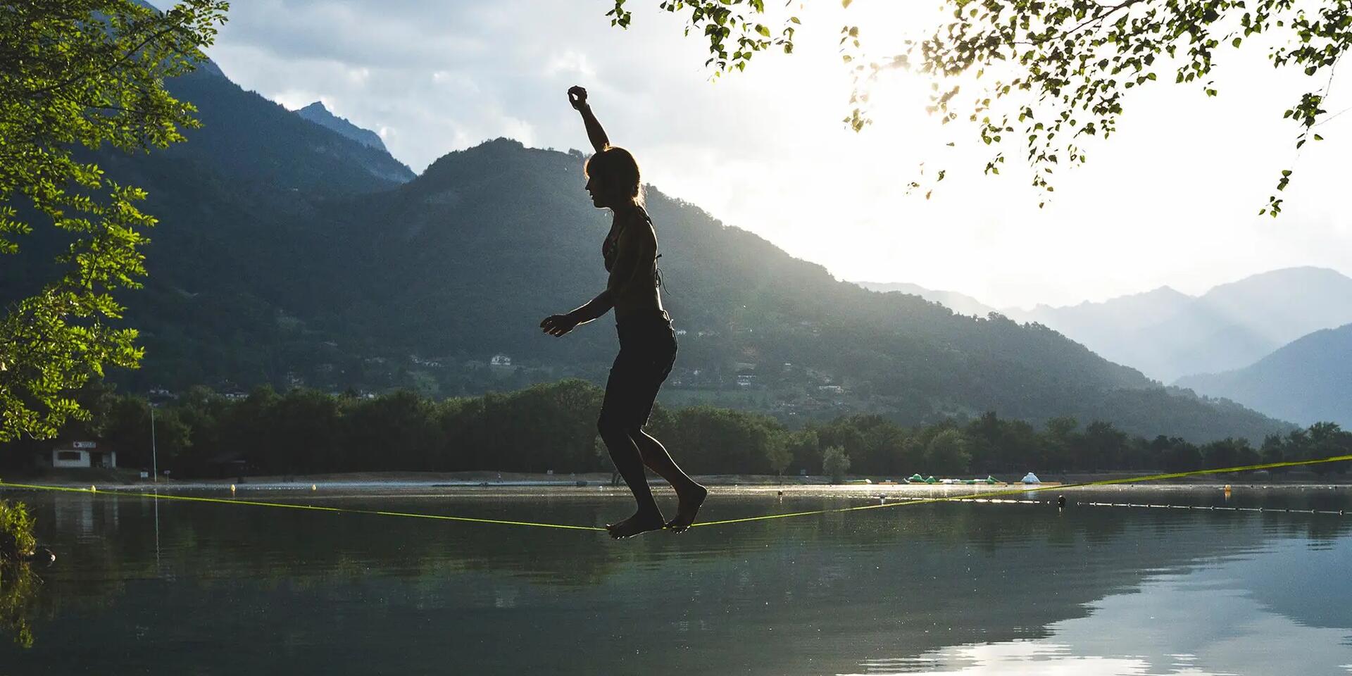 kobieta idąca po taśmie slackline nad wodą