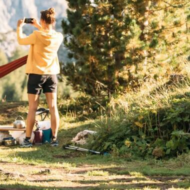 woman taking a picture of mountains during camping trip