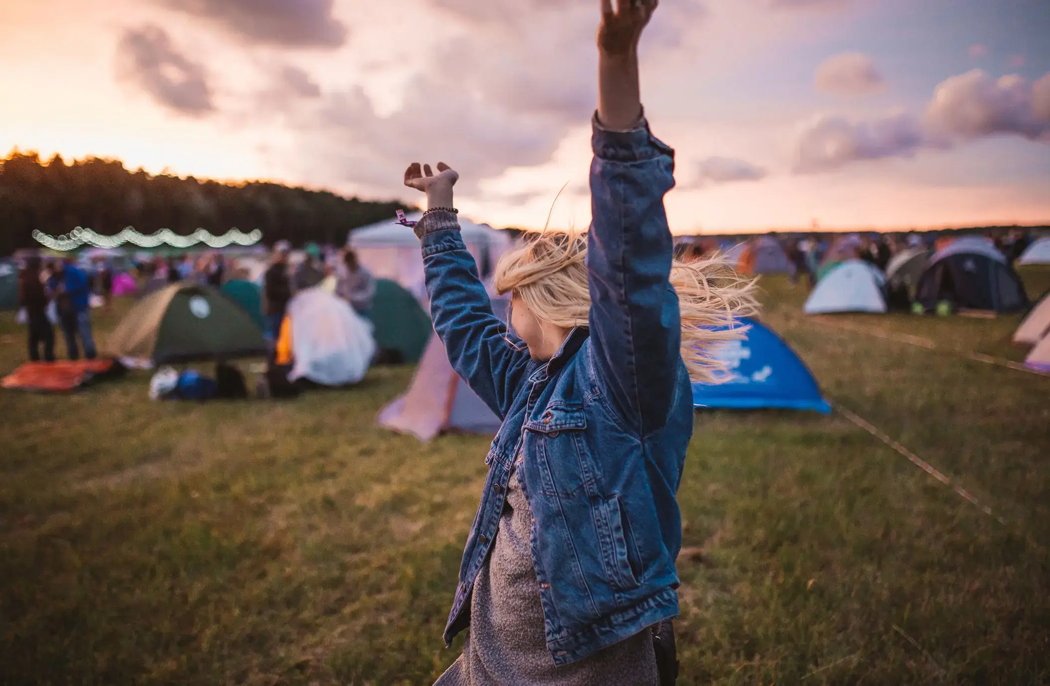 Mulher a dançar num festival com tendas atrás