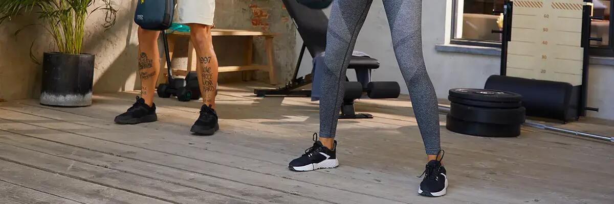 Ludzie w odzieży sportowej trenujący fitness wykonujący ćwiczenia z obciążeniem w butach sportowych o odpowiedniej budowie