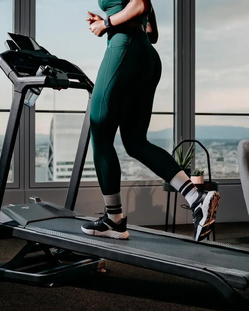 Eine Person nutzt ein Laufband mit Ausblick von einem Hochhaus-Fenster