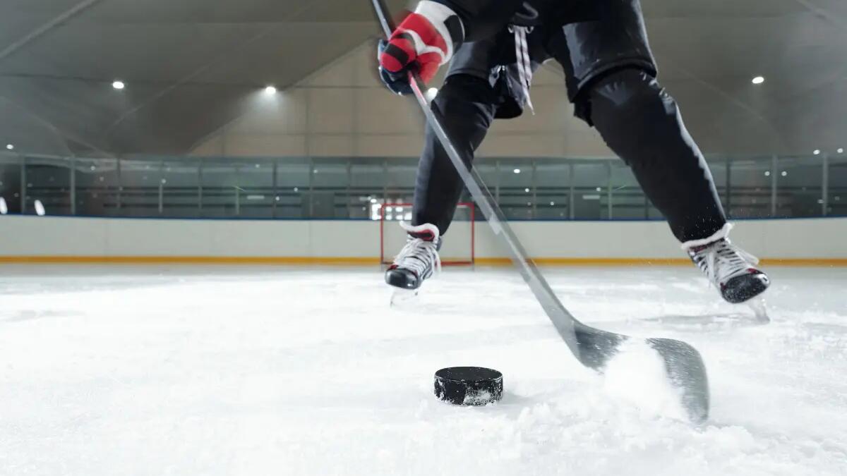 zawodnik w stroju i łyżwach hokejowych trenujący na lodowisku