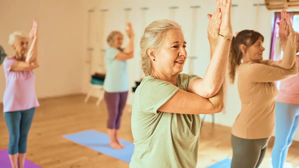 Kobiety w odzieży sportowej wykonujące proste ćwiczenia dla seniorów na sali treningowej