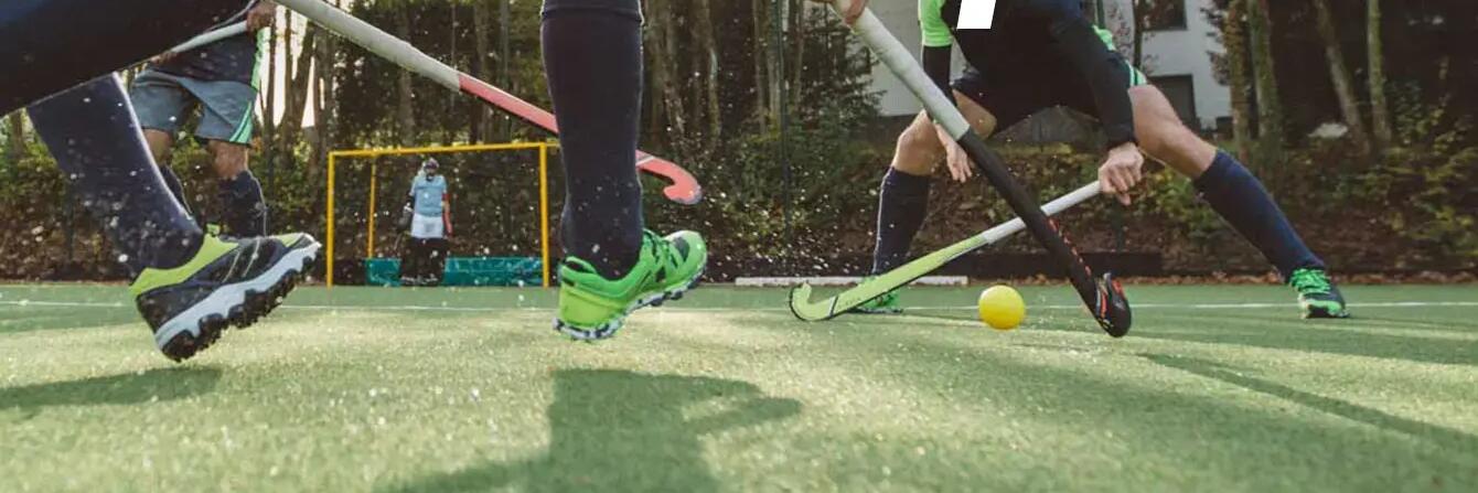 een team speelt veldhockey op een kunstgrasveld