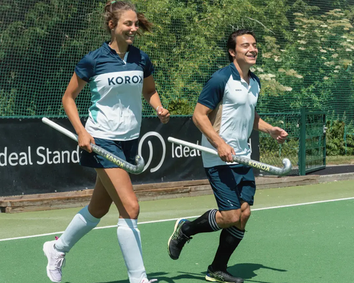 Twee hockeyspelers met scheenbeschermers aan op een hockeyveld