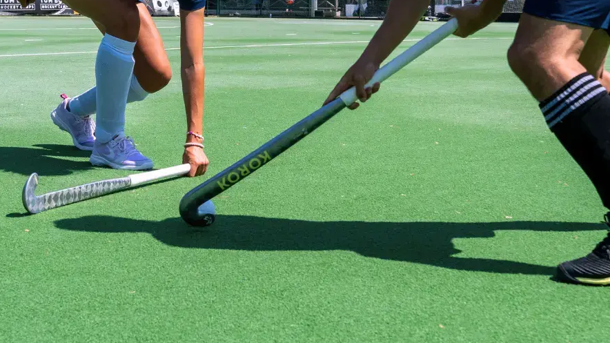 Twee hockeyspelers met sticks en scheembeschermers op een hockeyveld