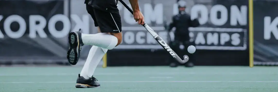 Een hockeyspeler op een veld die op doel mikt met een hockeystick