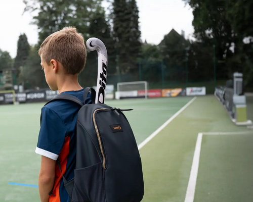 een jongen met een hockeytas op zijn rug