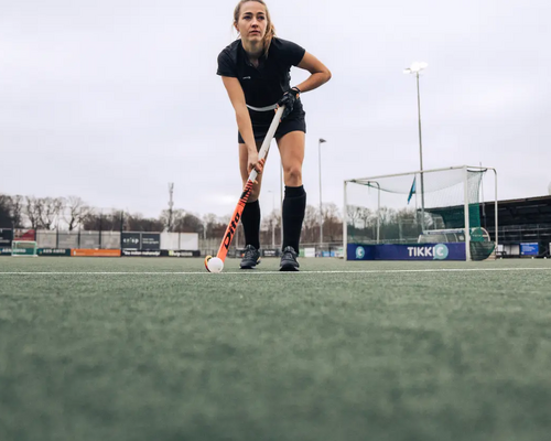 Een hockeyspeler met een stick en een bal op een hockeyveld